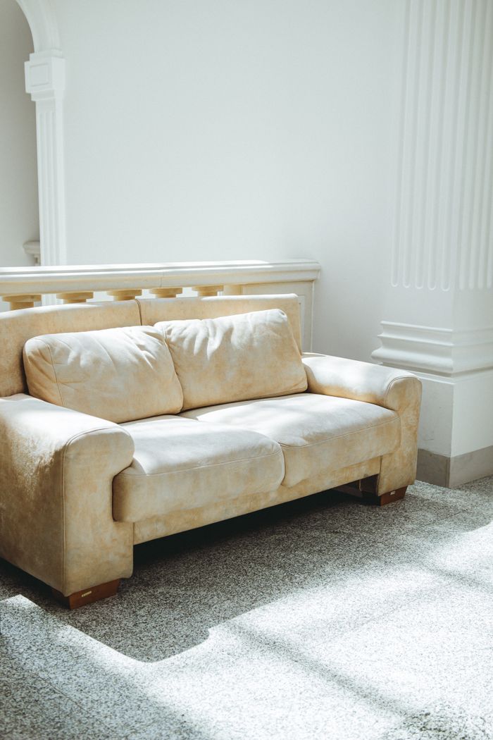 A luxurious beige sofa in a sunlit room with classic architectural details.