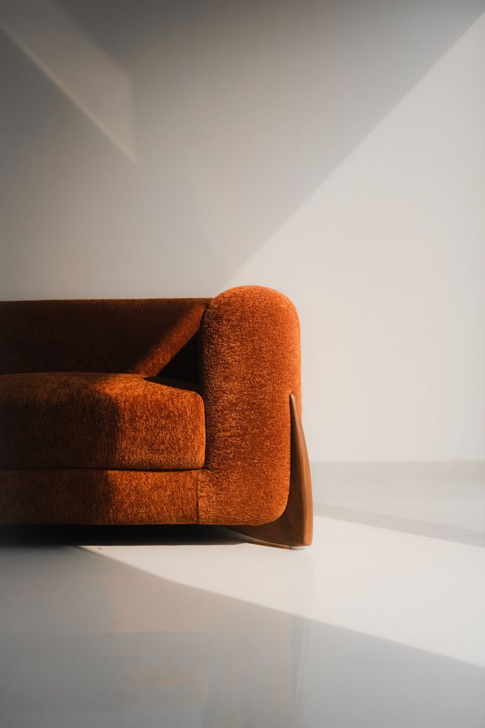 Sunlit modern orange sofa in minimalist room with sleek design.