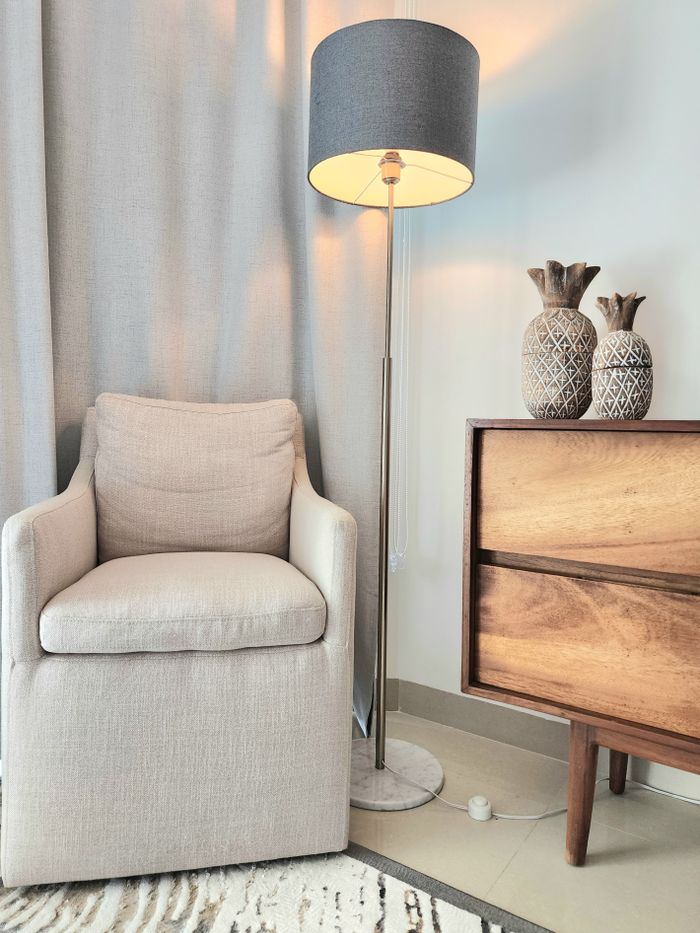 Elegant modern living room with armchair, lamp, and wooden dresser. Warm and inviting atmosphere.