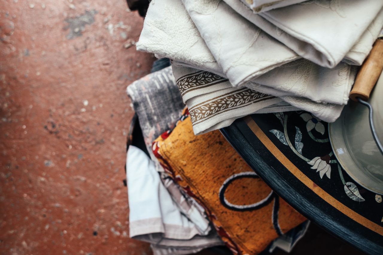 A collection of colorful and patterned textiles neatly stacked on a decorative table, showcasing vintage and retro designs.